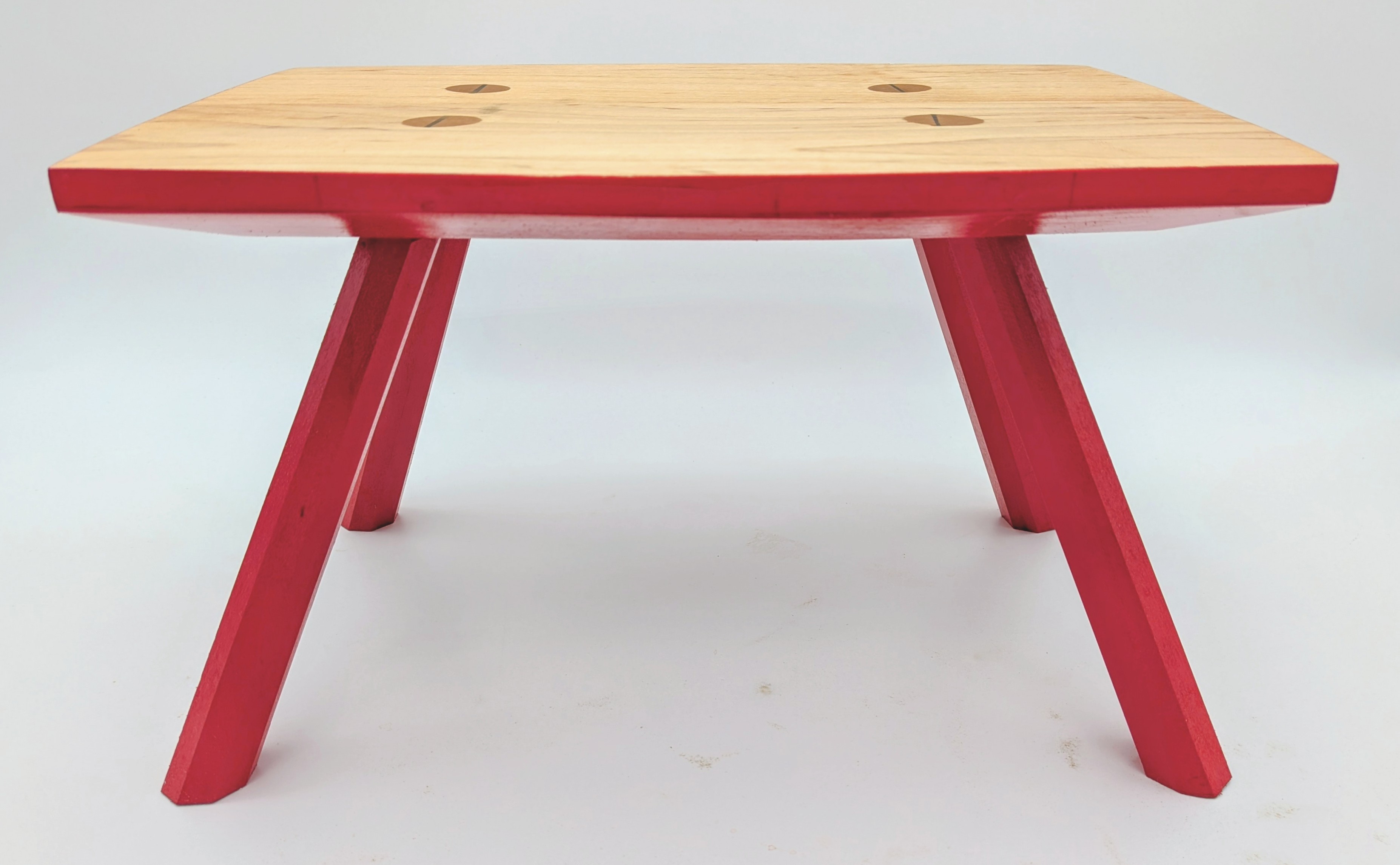 Foot stool with bright red base and maple top with wedged through-tenons.