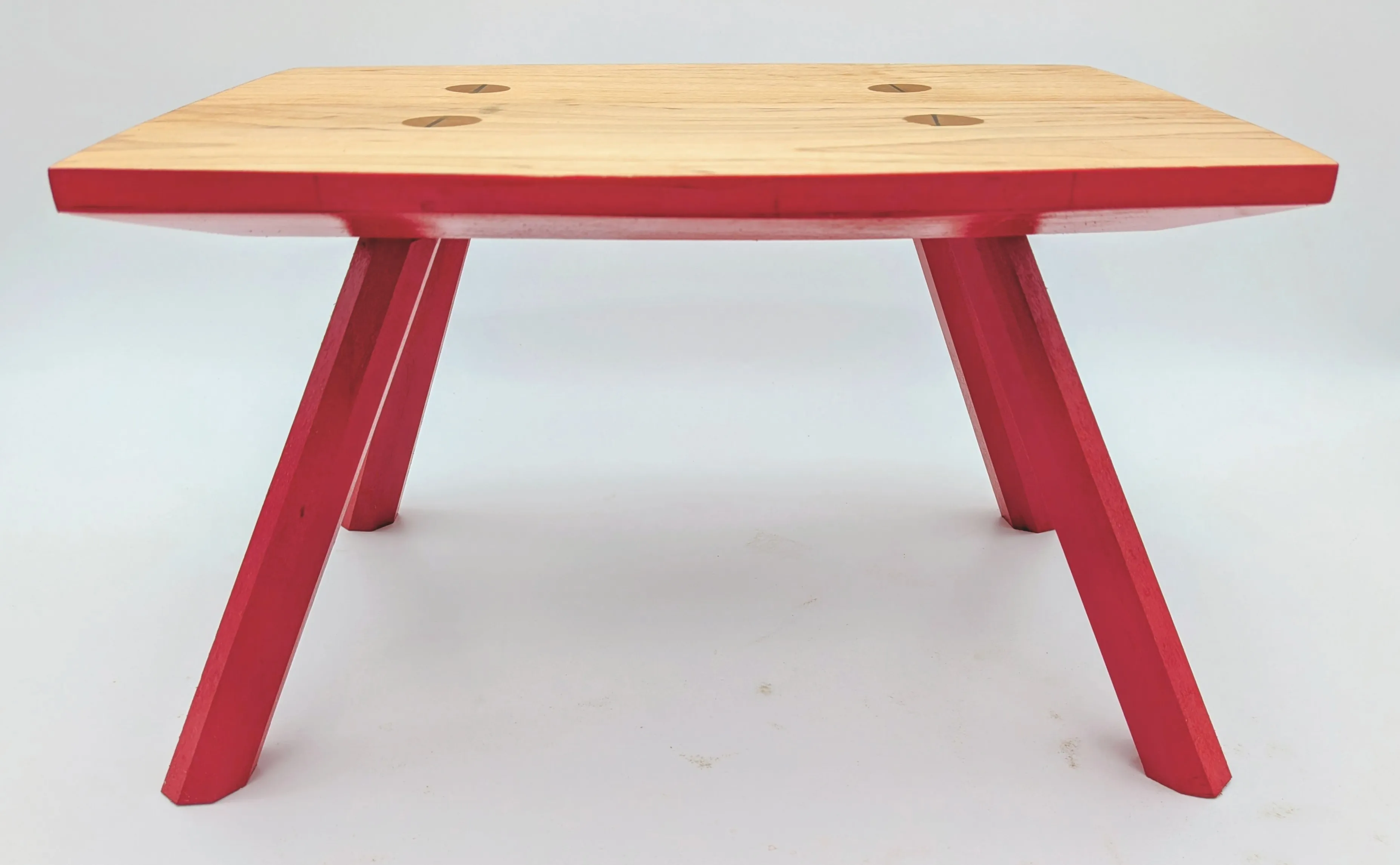 Foot stool with bright red base and maple top with wedged through-tenons.