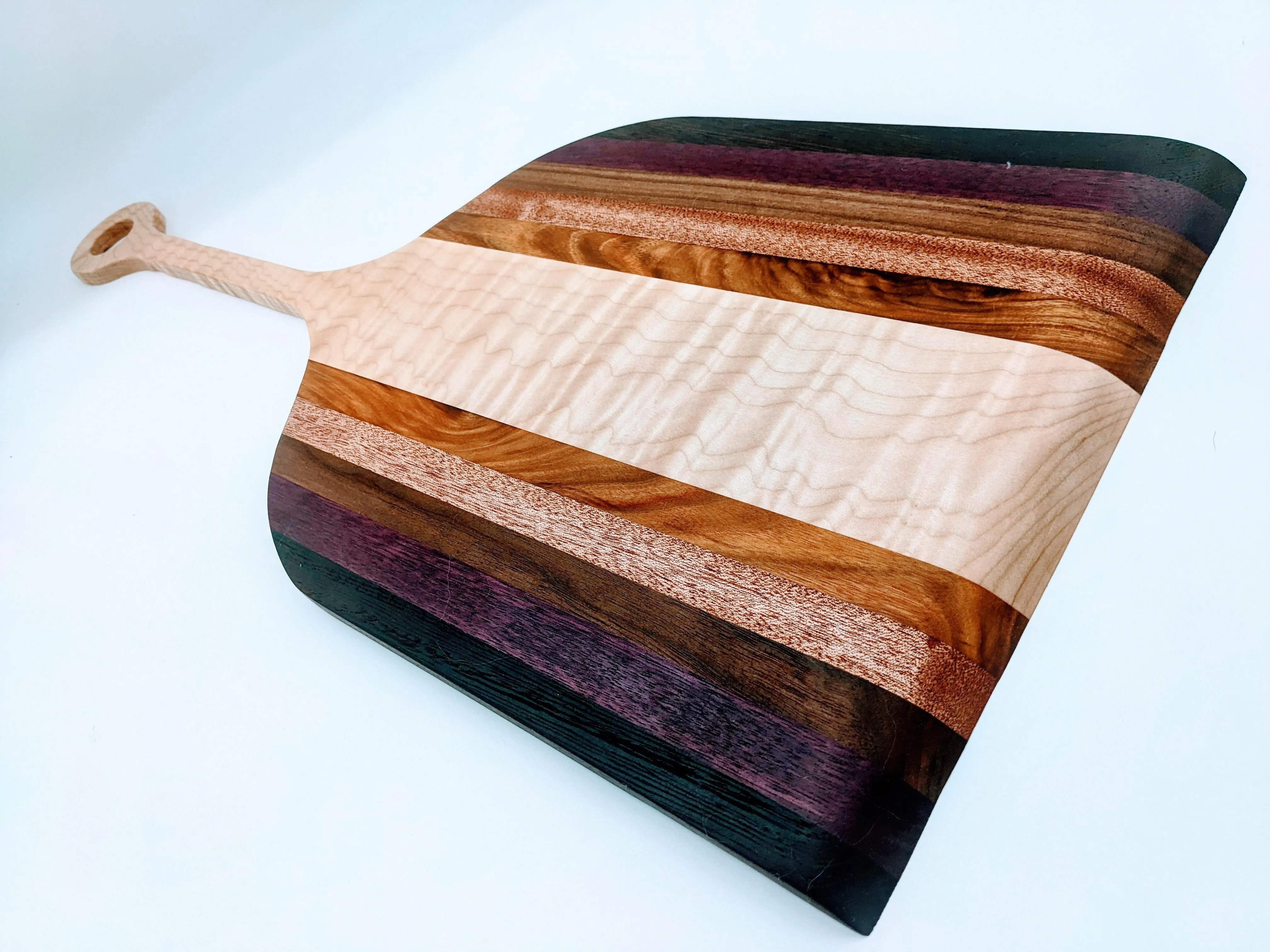 Wooden pizza peel with colorful woods.